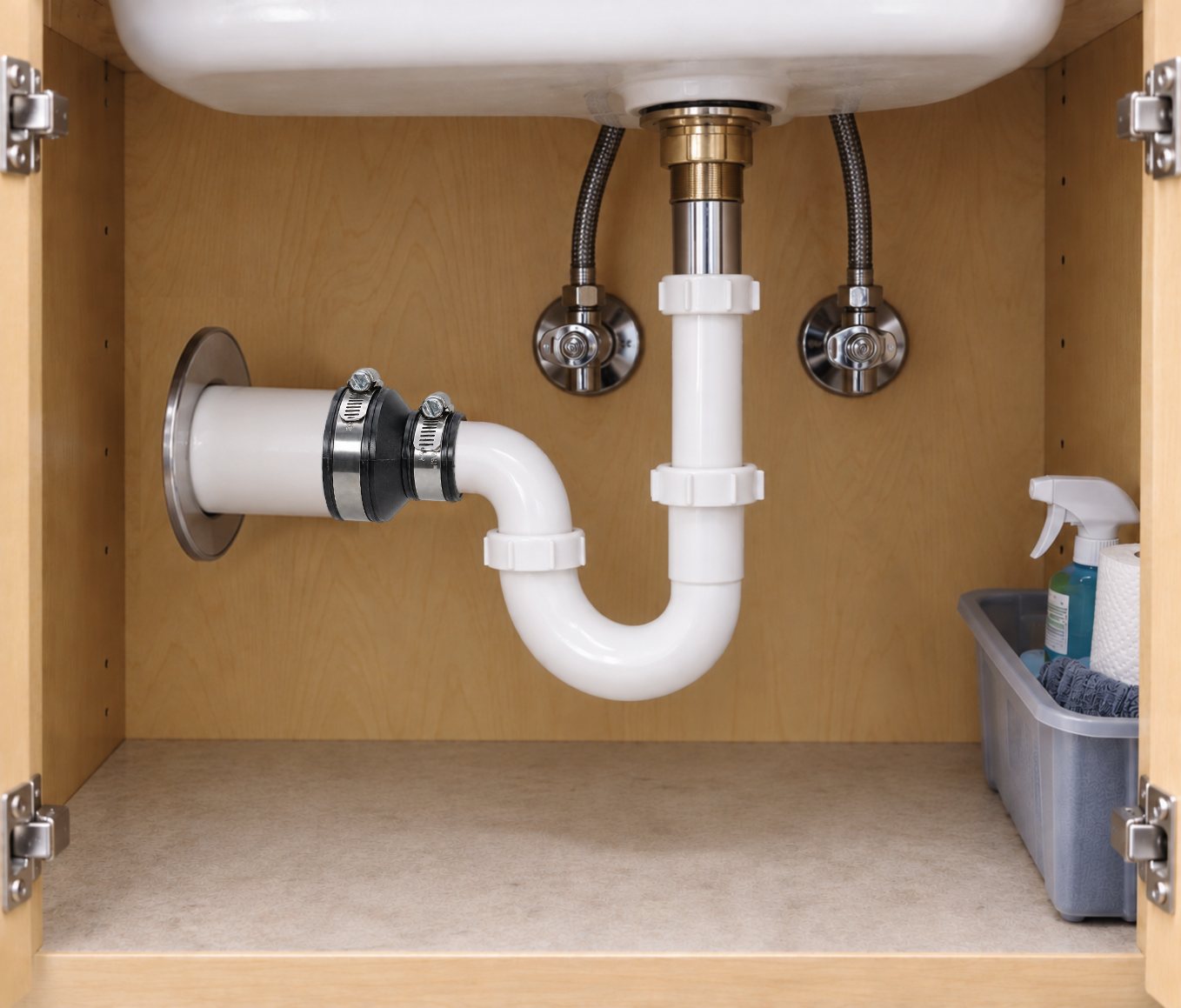 Fernco Drain & Trap Connector joining a white plastic sink trap to the drain pipe in a bathroom vanity cabinet