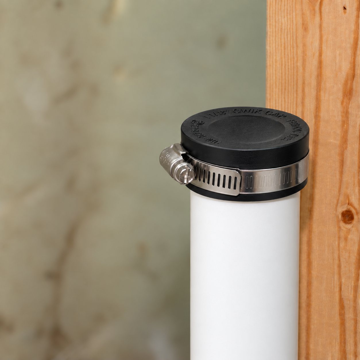 Fernco Qwik Cap clamped on the end of a white PVC stub-out next to a wall stud